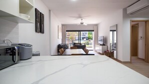 A modern kitchen with a large island, microwave, and a dining area with chairs and a table. - Bran new condo with pool access (Bavaro)