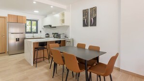 A modern kitchen with a central island, a dining table with chairs, and artwork on the wall. - Bran new condo with pool access (Bavaro)