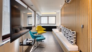 A modern interior with a long bench, a sofa, and two chairs. - GSM Elevated Luxury Suites (Athens)