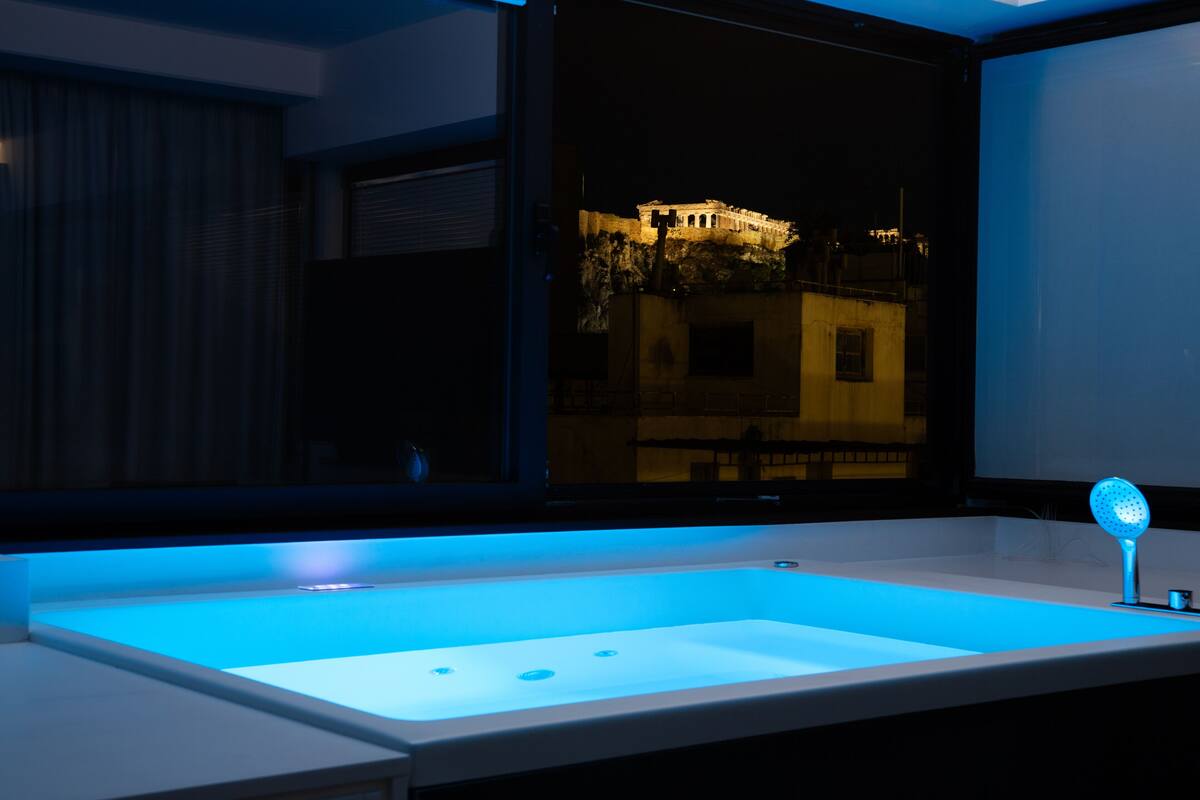 A bathroom with a large window, a sink, and a blue light under the window.