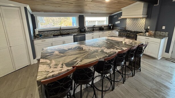 A modern kitchen with a large island, dark walls, and wooden ceiling. - The Salty Dog (Conway)