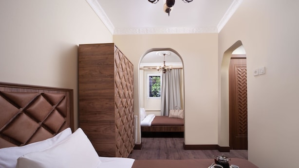 Una camera d'albergo con un letto grande, un'area salotto più piccola e vista sull'esterno da una finestra.