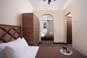 Una camera d'albergo con un letto grande, un'area salotto più piccola e vista sull'esterno da una finestra.