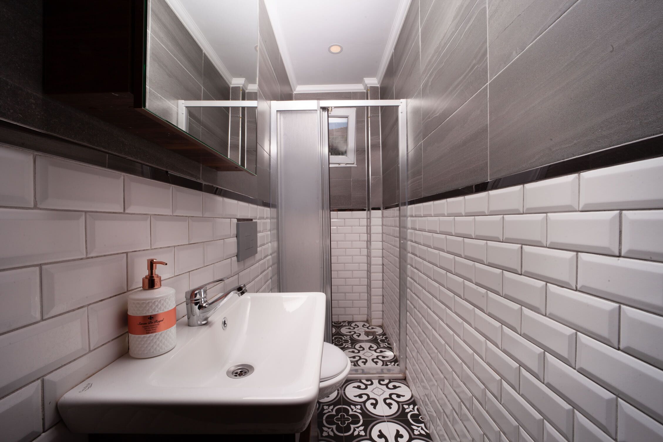 A modern bathroom with a white sink, a toilet, and a shower area.