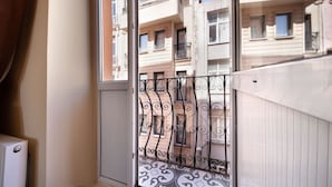 Vista da un balcone con ringhiere in ferro battuto, che si affaccia su edifici vicini con balconi e finestre.