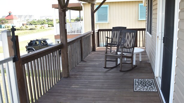 A wooden deck with a railing, two rocking chairs, and a small rug. - Beach Cottage, 3 min walk to Beach Kill Devil Hills with WiFi, AC, Hot Tub (Kill Devil Hills)