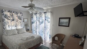 A bedroom with a bed, a desk, a chair, a ceiling fan, and a window with curtains. - Beach Cottage, 3 min walk to Beach Kill Devil Hills with WiFi, AC, Hot Tub (Kill Devil Hills)