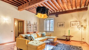 A cozy living room with a sofa, two side tables, a patterned rug, and wooden beams on the ceiling. - Spacious and wonderful apartment in the historic center with pets allowed (Lucca)