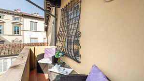A balcony with wicker furniture, a table with a tray of tea items, and a decorative wall panel. - Spacious and wonderful apartment in the historic center with pets allowed (Lucca)