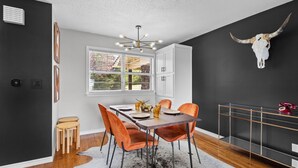 Un comedor con una mesa preparada para cuatro, una lámpara moderna tipo candelabro y una decoración de cráneo de toro en la pared.