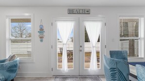 A room with a white door labeled "BEACH," a blue sofa, and a patterned rug.