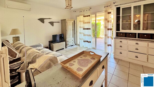 Una sala de estar con un sofá, un televisor, un mueble y una ventana con cortinas.