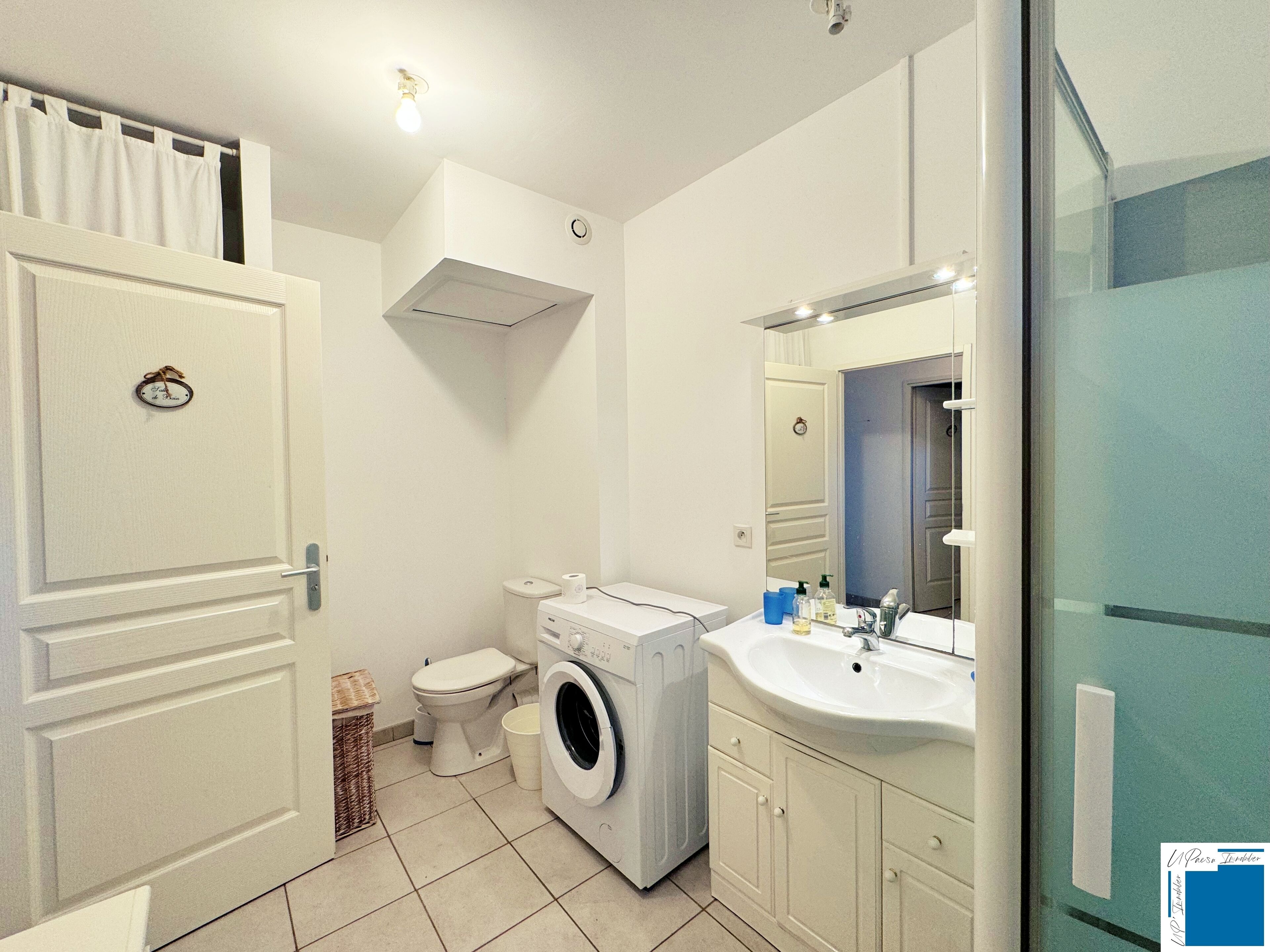 Un baño pequeño con inodoro, lavadora y lavamanos.