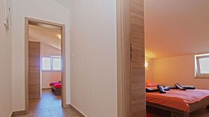 A hotel room with a bed, a bedside table, a window, and a door leading to another room. - Holiday apartment with terrace and parking (Ližnjan)