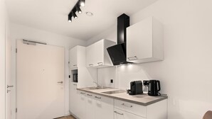 Una cocina moderna con armarios blancos, una campana extractora negra y una cafetera sobre la encimera.