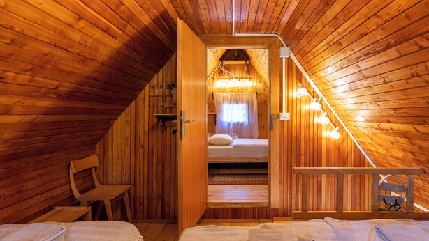 Een houten chalet met een slaapkamer op de zolder, een houten stoel en een kleine tafel.