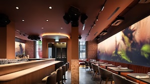 A restaurant interior with a bar area, seating, and a large wall with a nature-themed mural. - SonoLux (Montréal)