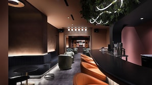 A modern bar area with leather seating, a long counter, and ambient lighting. - SonoLux (Montréal)