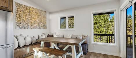 Cozinha moderna com mesa de jantar de madeira, bancos e um detalhe decorativo na parede.