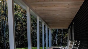 Eine überdachte Veranda mit weißen Säulen, Holzterrasse und Außenmöbeln.