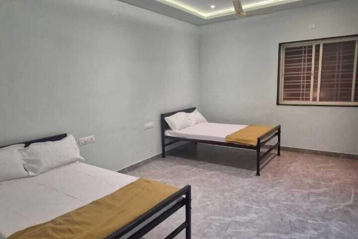 A room with two beds, a ceiling fan, recessed lighting, and a window with blinds.