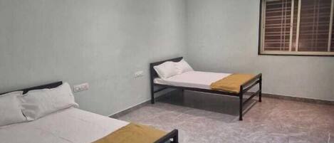 A room with two beds, a ceiling fan, recessed lighting, and a window with blinds.