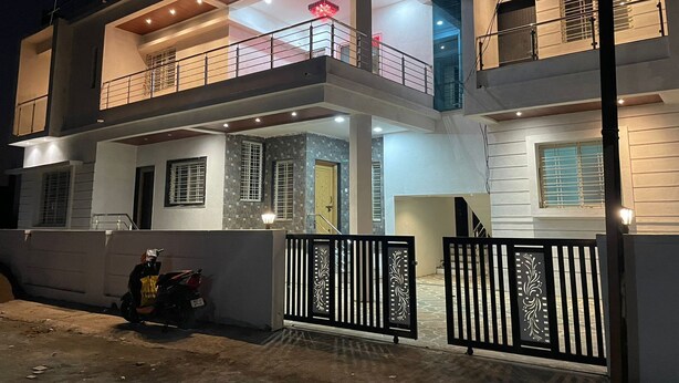A two-story residential building with a balcony on the upper floor, a gated entrance, and a parked motorcycle. - Shri Swami Samarth Home Stay (Akalkot)