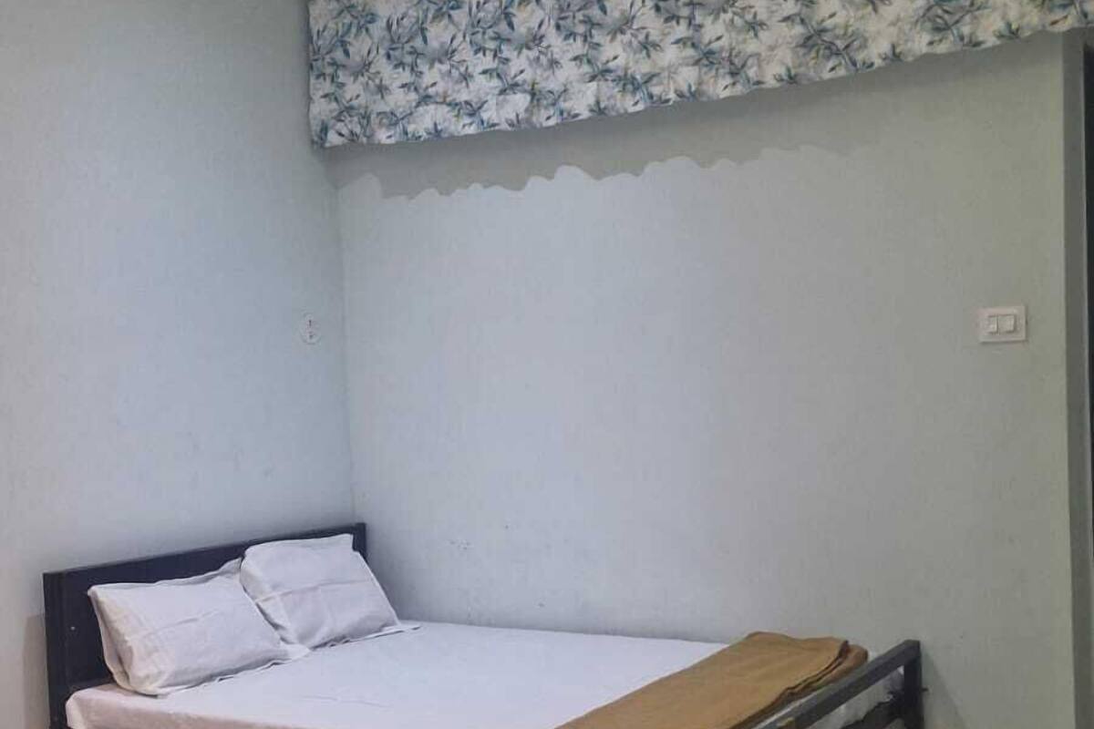A single bed with a headboard, a ceiling fan, and a floral-patterned valance.