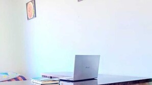 A reception desk with a laptop, framed pictures on the wall, and a patterned carpet. - Shri Swami Samarth Home Stay (Akalkot)