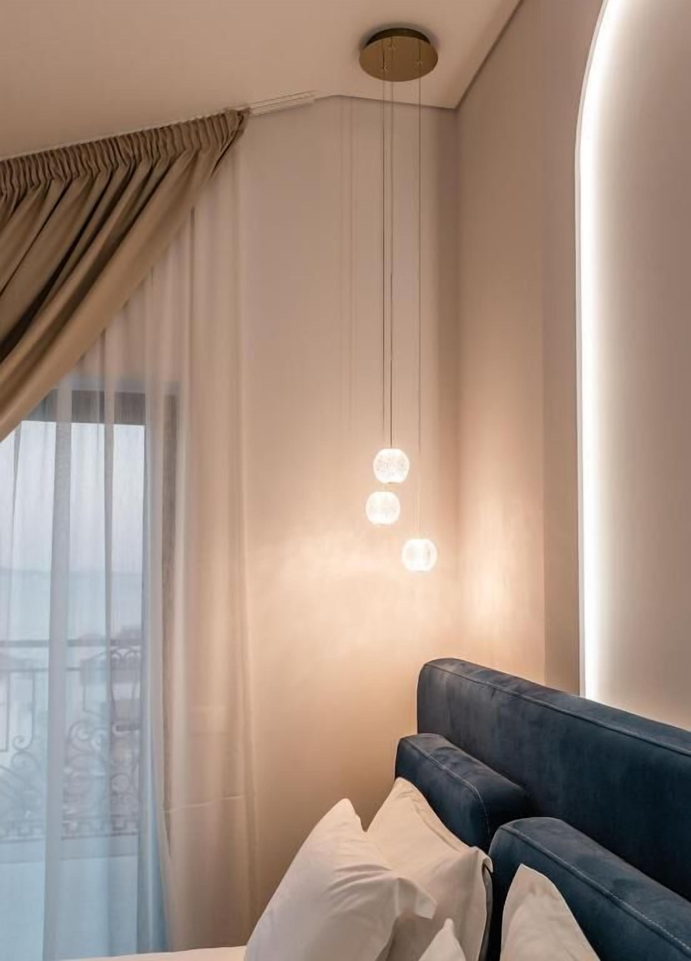 A modern hotel room with a large window, a blue sofa, and a hanging light fixture.
