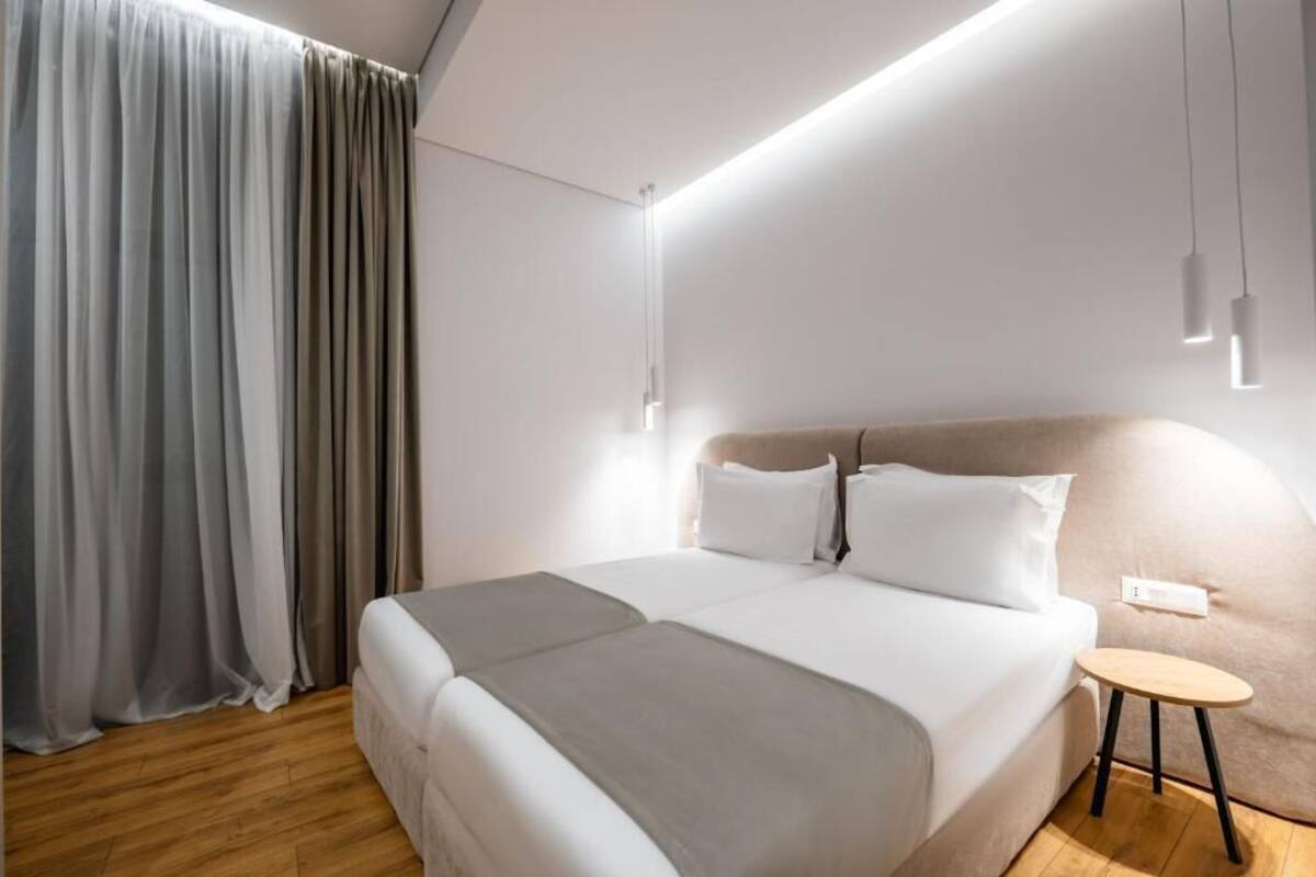 A modern hotel room with a large bed, a small round table, and a ceiling light fixture.