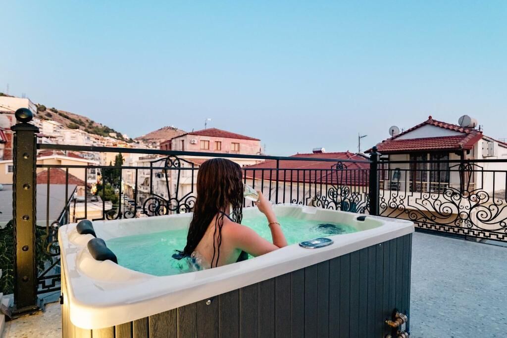 A person relaxing in a hot tub with a view of buildings in the background.