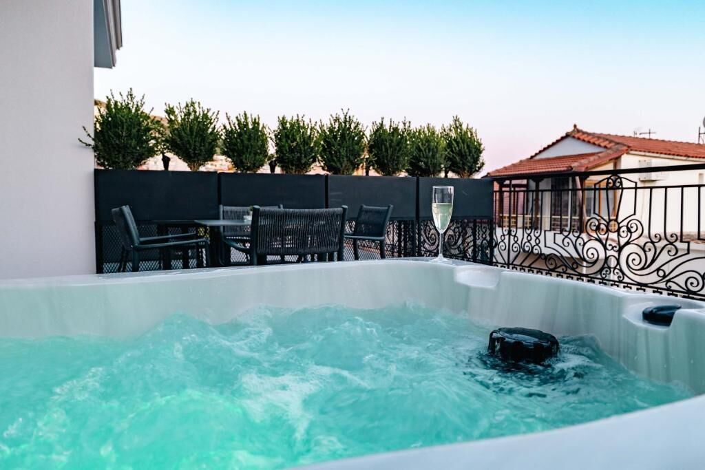Un jacuzzi con una mesa y sillas, rodeado por una cerca decorativa y follaje.