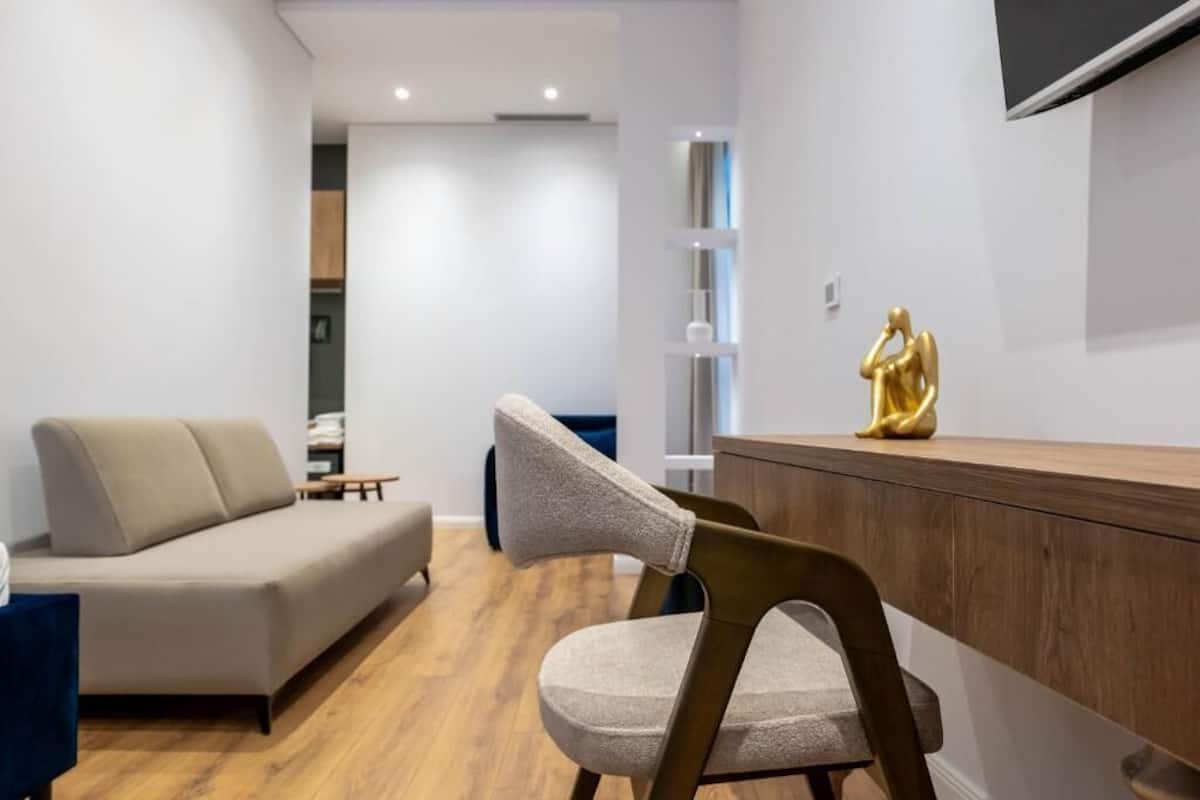 A modern living room with a sofa, a wooden sideboard, and a chair.