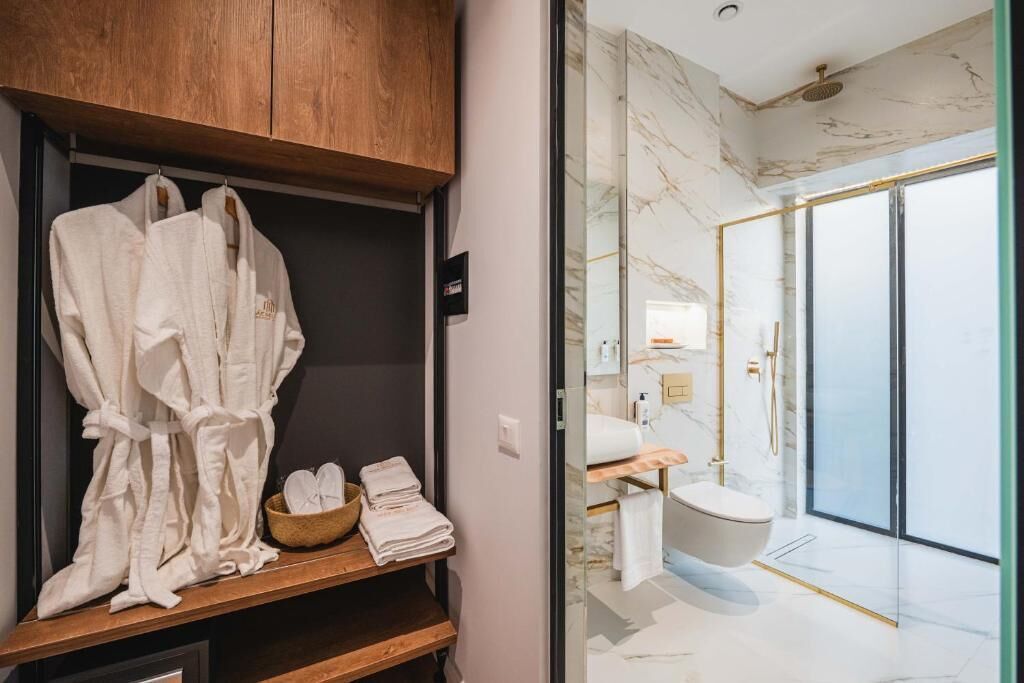 A modern bathroom with a marble floor, a freestanding toilet, and a glass-enclosed shower area.