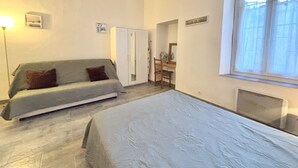 A bedroom with a bed, a sofa, a desk, and a window.
