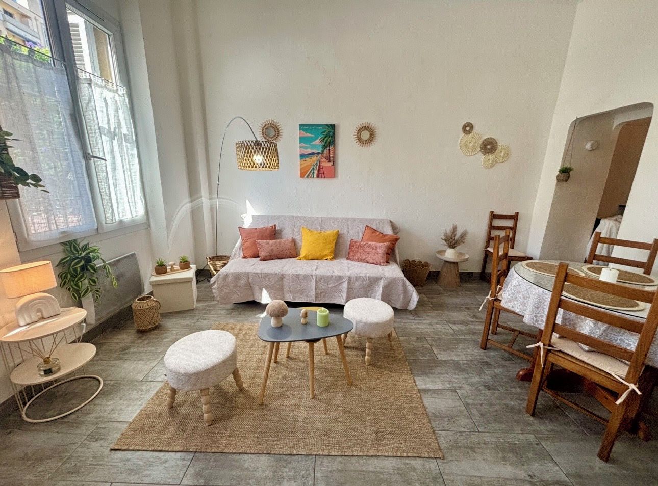 A living room with a sofa, coffee table, and chairs, a dining table with chairs, and a window with a view.