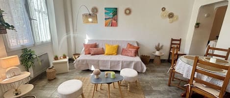 A living room with a sofa, coffee table, and chairs, a dining table with chairs, and a window with a view.
