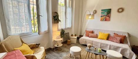 Una sala de estar acogedora con sofá, otomanas, una mesita y una silla.