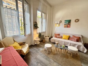Un salon confortable avec un canapé, des poufs, une petite table et un fauteuil.