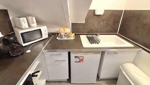 A compact kitchenette with a microwave, coffee maker, and small refrigerator.
