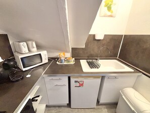 Une petite cuisine équipée d’un four à micro-ondes, d’une machine à café et d’un petit réfrigérateur.