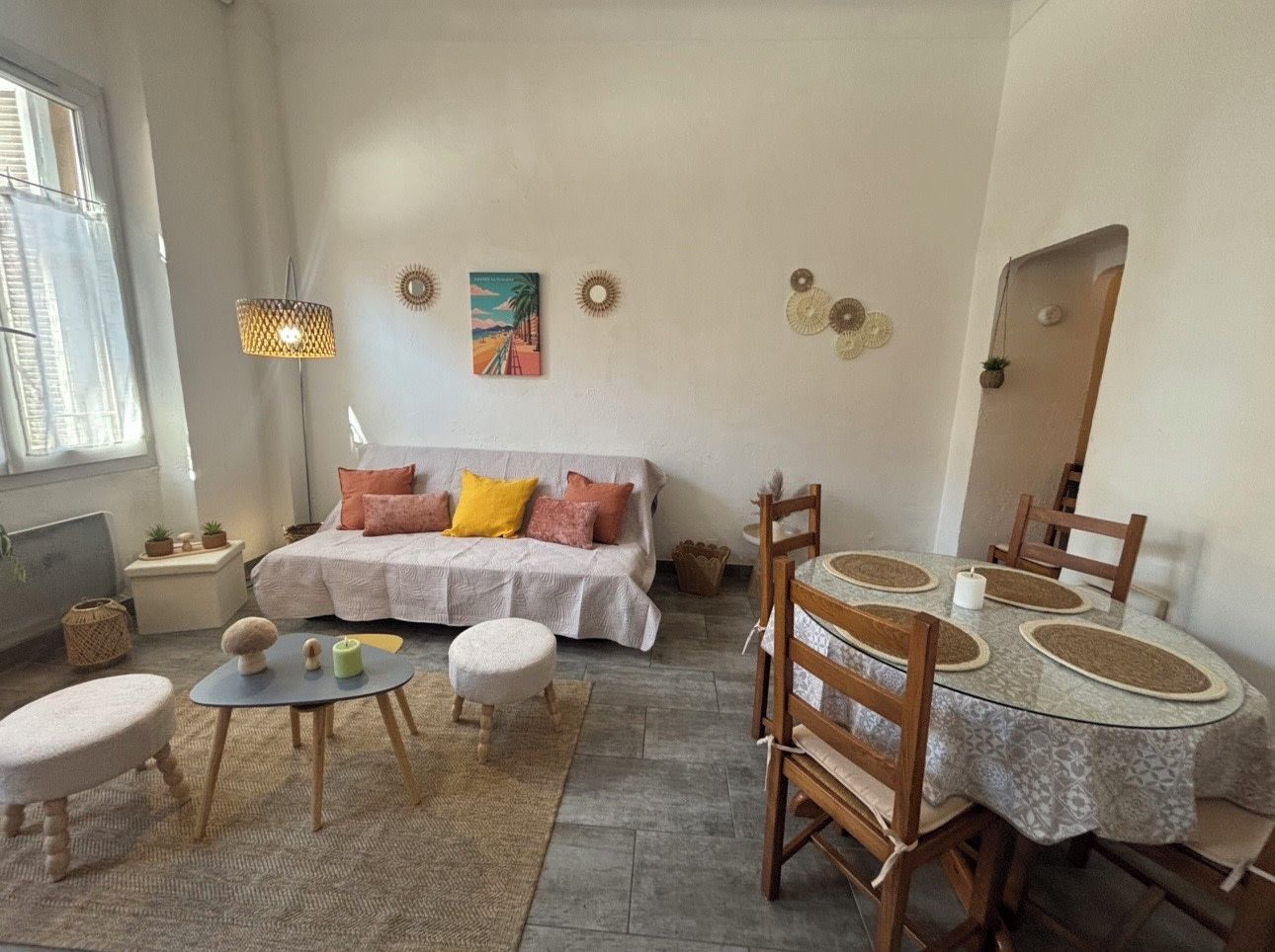 A cozy living room with a sofa, a round dining table, and a small round table.