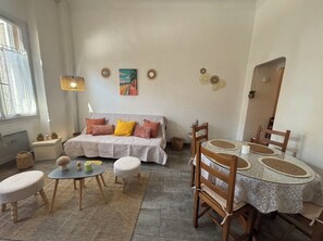 Un salon chaleureux avec un canapé, une table de salle à manger ronde et une petite table ronde.