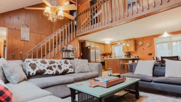 Un salon spacieux avec un grand canapé, une table basse et un escalier menant à l’étage supérieur.