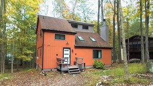 Une maison à deux étages avec une façade rouge, une porte de garage blanche et une cheminée.