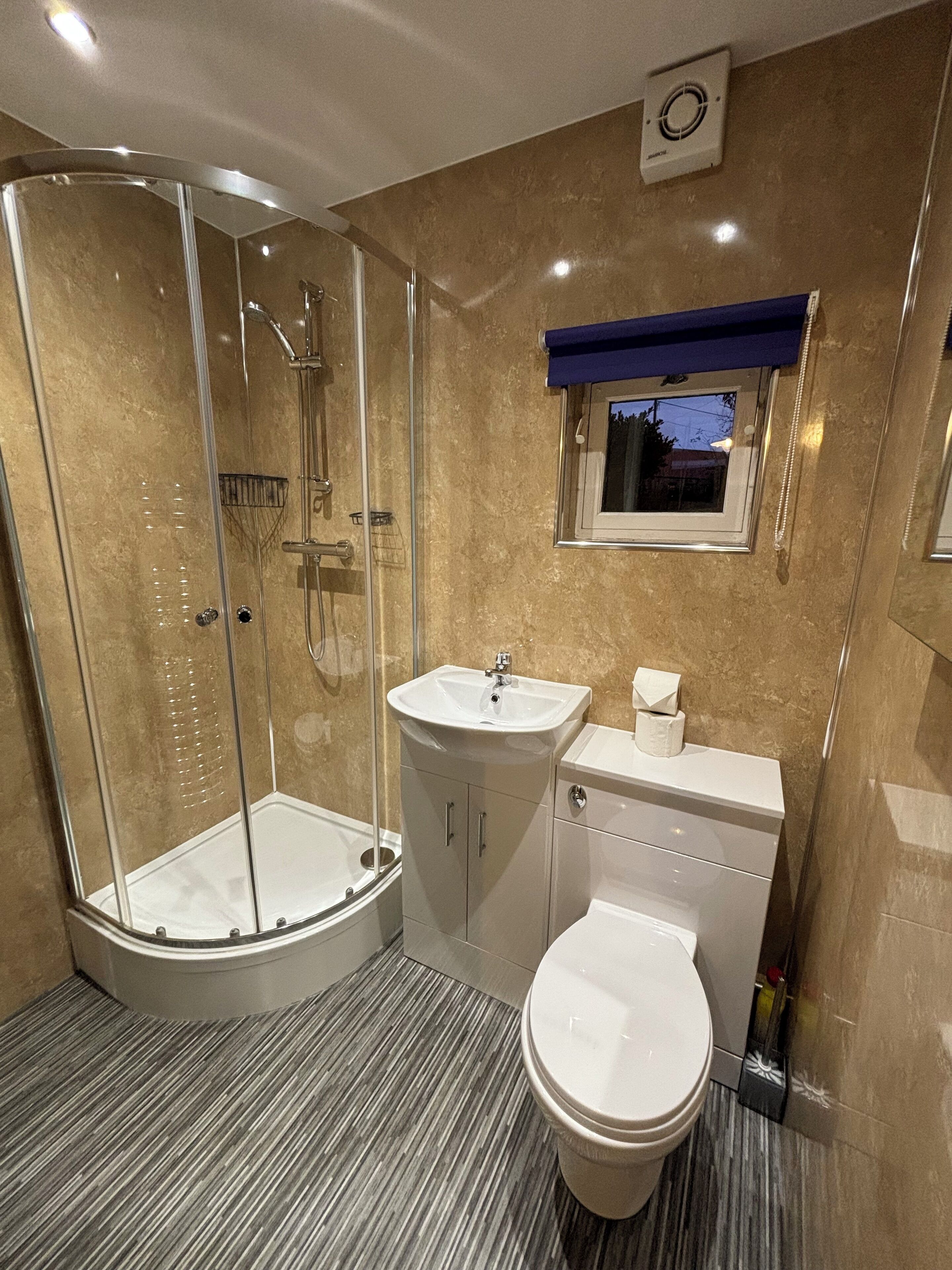 A modern bathroom with a glass-enclosed shower, a sink, and a toilet.