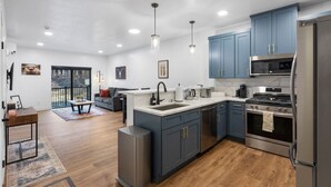 A modern kitchen with blue cabinets, stainless steel appliances, and a central island. - Gateway to Alaska Wonders A308 (Juneau)