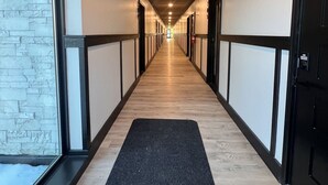 A long, narrow hallway with a wooden ceiling, black-framed doors, and a black carpet runner. - Gateway to Alaska Wonders A308 (Juneau)