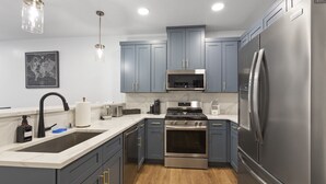 A modern kitchen with grey cabinets, stainless steel appliances, and a wooden floor. - Juneau Jewel: Luxury & Relaxation A307 (Juneau)